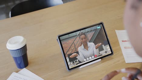 Caucasian-businesswoman-on-tablet-video-call-with-biracial-female-colleague-on-screen