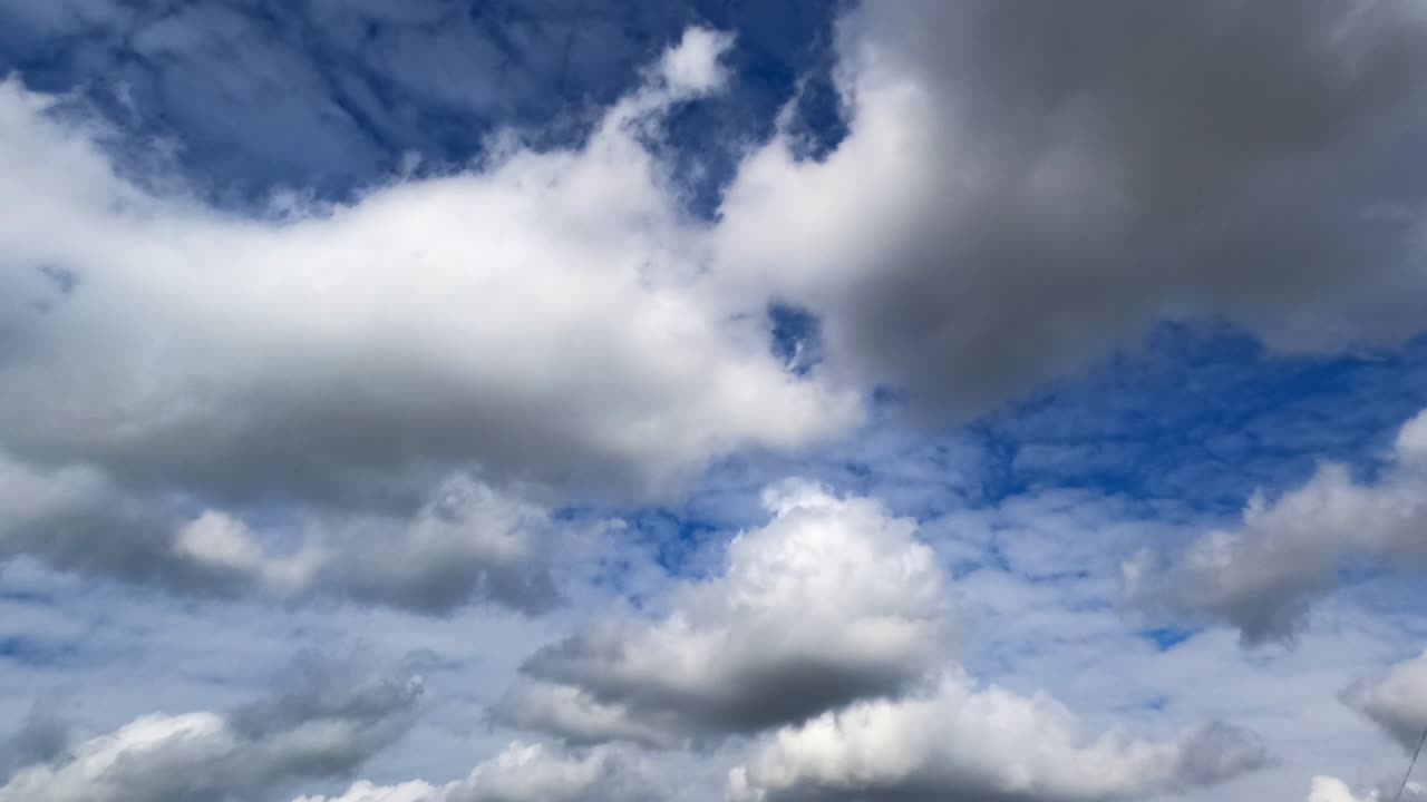 Soft fluffy clouds in the amazing azure sky. Cirrocumulus and cumulus cloudscape arrives and covers the horizon. Low angle view. Timelapse.