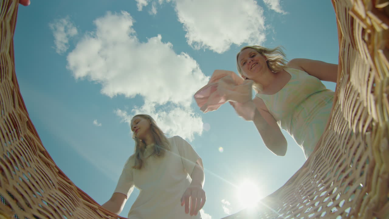 두 여자 가 바구니 에 세탁 을 넣고 있다