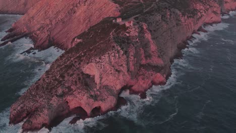 reveal shot of high cliff at farol do cabo espichel portugal with sunrise, aerial