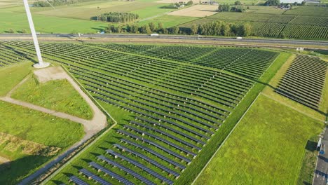 Dron-Volando-Lentamente-Junto-A-Una-Granja-De-Paneles-Solares-Fotovoltaicos-Junto-A-Una-Carretera-Muy-Transitada