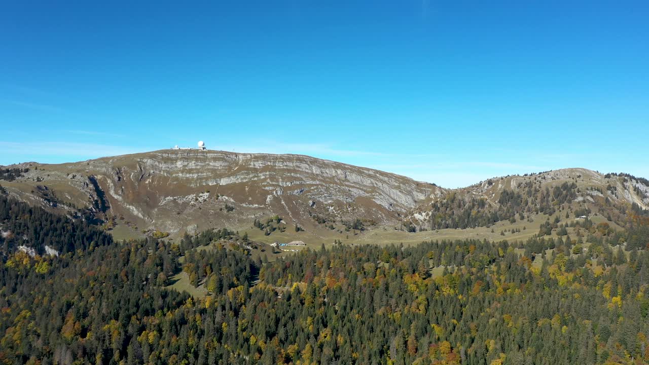 un dron vuela sobre un bosque alpino con vistas a un gran lago y en la neblina lejana una vista majestuosa del mont blanc picos masivos y altos de los alpes suizos y franceses