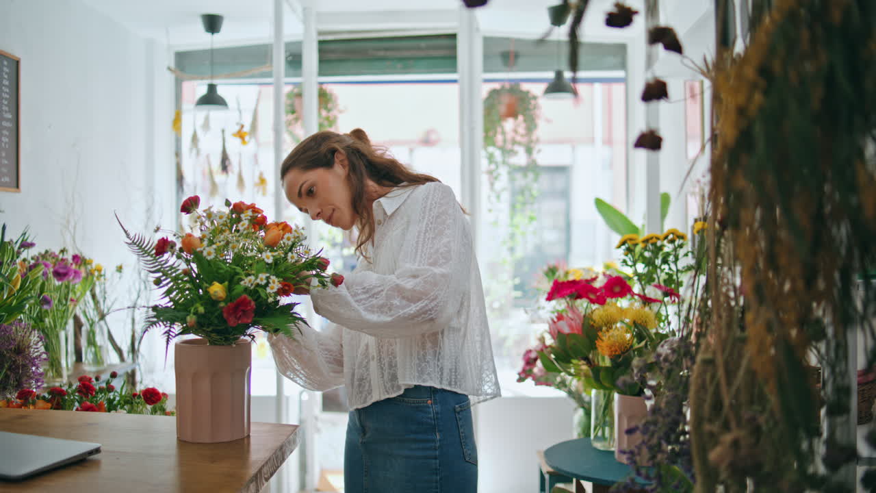 Fiorista indaffarata prepara un bouquet nel negozio di fiori. Lavoro del proprietario di piccola impresa