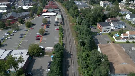 Drohne-Fliegt-Entlang-Der-Bahngleise-Und-Nähert-Sich-Dem-Parkplatz-Des-Bahnhofs-Northampton,-Massachusetts