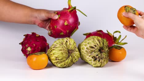 hands selecting and removing fruits from a pile