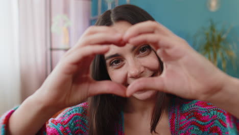 happy young woman girl makes symbol of love showing heart sign to camera express romantic feelings