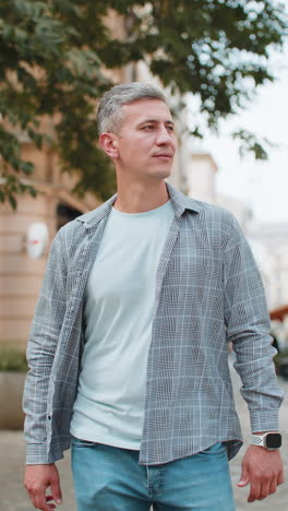 smiling mature man in casual clothes walking in urban city street background in summer outdoors