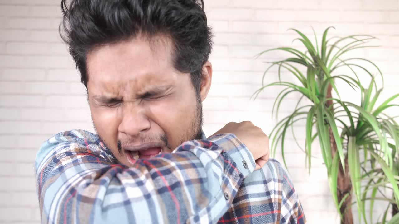 肘に咳をかける男