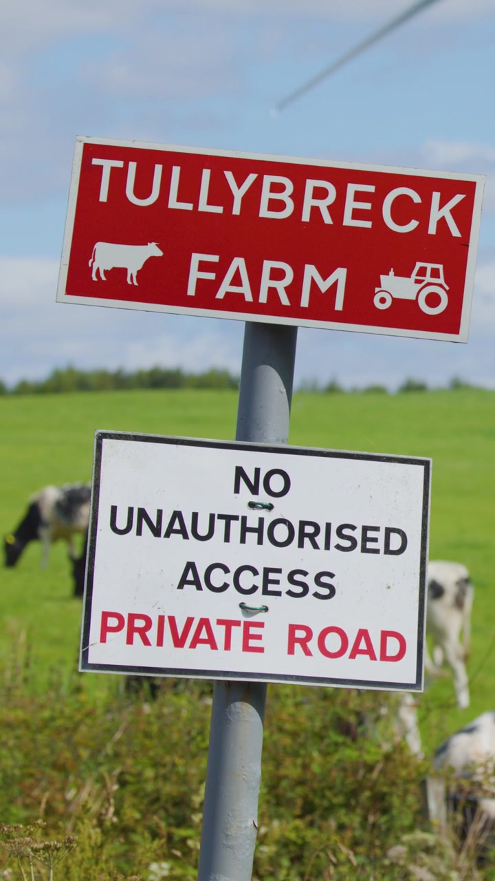 A warning sign at Tullybreck Farm marks a private road with no unauthorized access, set against a bright, rural landscape with grazing cows