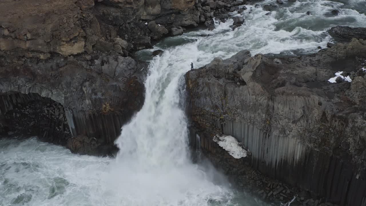 hombre de pie en el borde del acantilado y disfrutando de la caída de la cascada en islandia