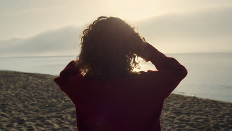 chica elegante caminando por la orilla del mar por la mañana. mujer disfrutando de las luces del amanecer
