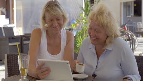 Dos-Mujeres-Mayores-Viendo-Fotos-En-La-Plataforma-En-El-Café-De-La-Calle