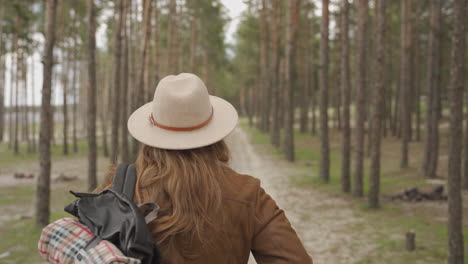 Eine-Unerkennbare-Abenteuerlustige-Rothaarige-Camperin,-Die-Durch-Die-Bäume-Eines-Waldes-Geht