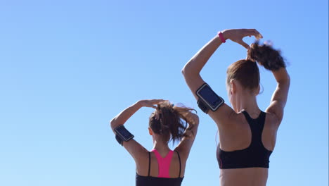 two athletic friends stretching on promenade before run