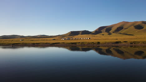 Revealing-drone-shot-of-a-small-yurt-village-beside-the-Song-Kol-lake-in-Kyrgyzstan