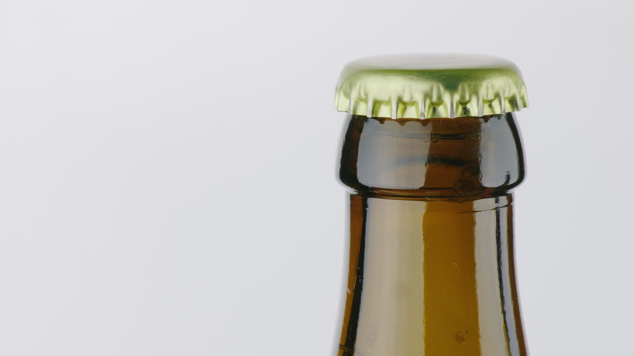 el cuello de una botella de cerveza está cubierto con una tapa de metal en un video de 4k de fondo blanco