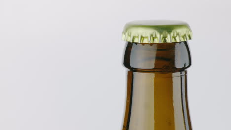 the neck of a bottle of beer is covered with a metal lid on a white background 4k video