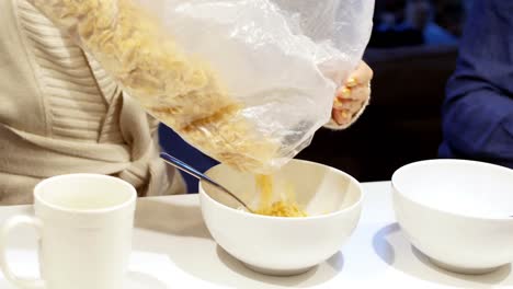 Mid-section-of-woman-pouring-cereals-in-bowl