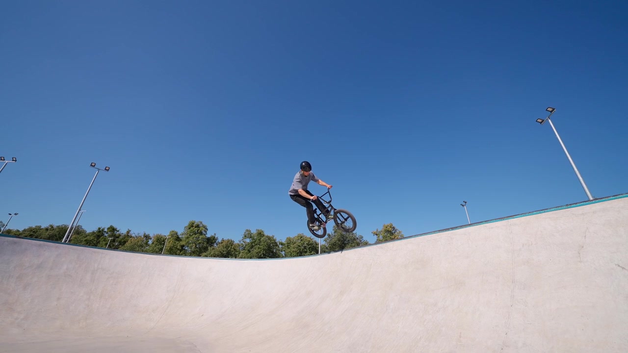 Ung mand kører på BMX-cykel og udfører trick i skatepark