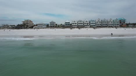 vacation houses on white-sand beach facing the gulf of mexico in panama city beach, florida. wide drone approach