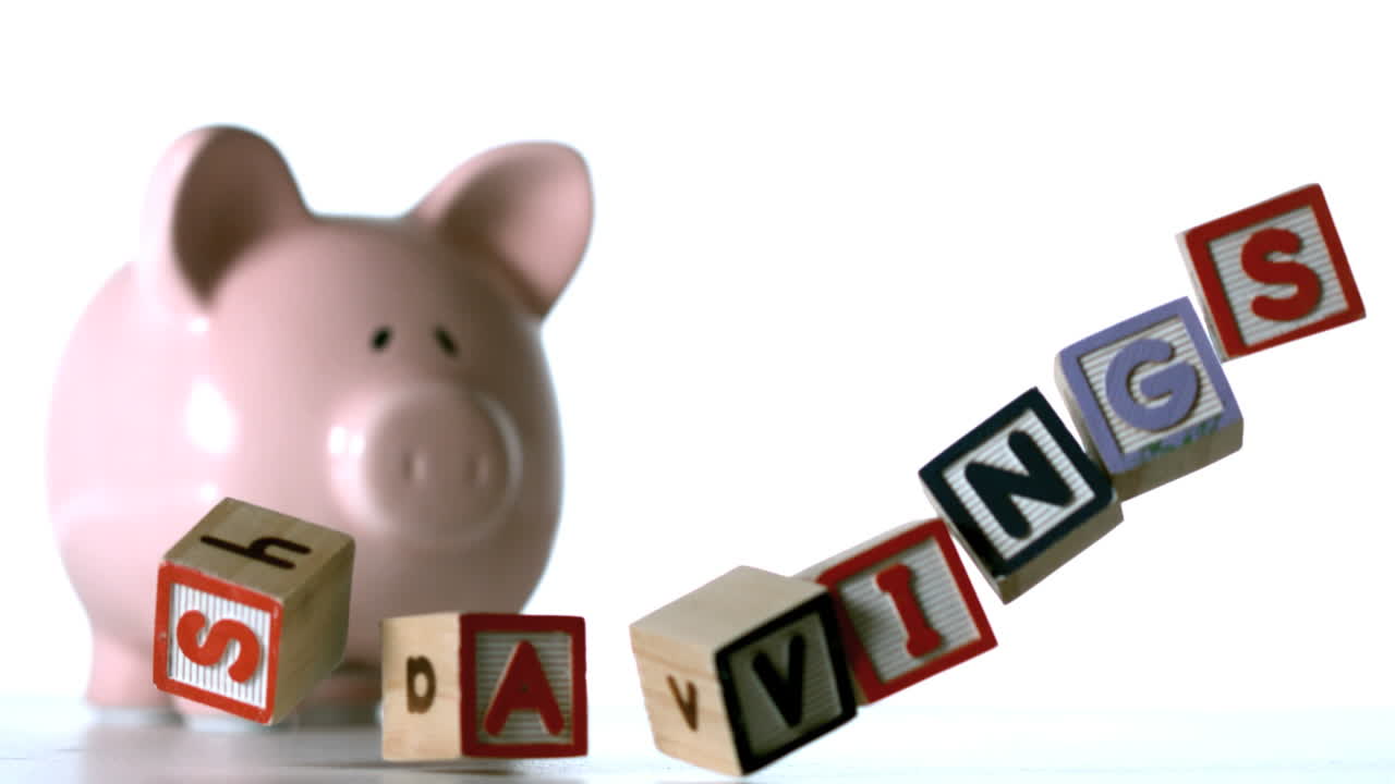 핑크색 돼지 은행 앞에 떨어지는 저축을 철자하는 블록