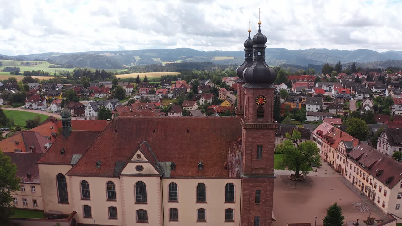 Old church building with clock tower in a scenic town, mountains in the background