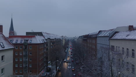 Forwards-tracking-of-vehicles-driving-on-wide-street-between-multistorey-apartment-houses.-Winter-in-city.-Berlin,-Germany