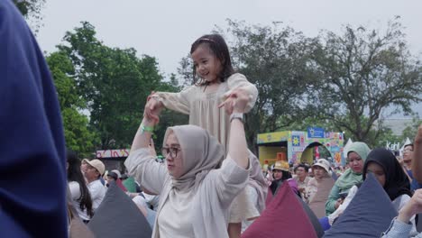 happy indonesian people enjoying an outdoor music concert and festival event for kids, families, and adults.