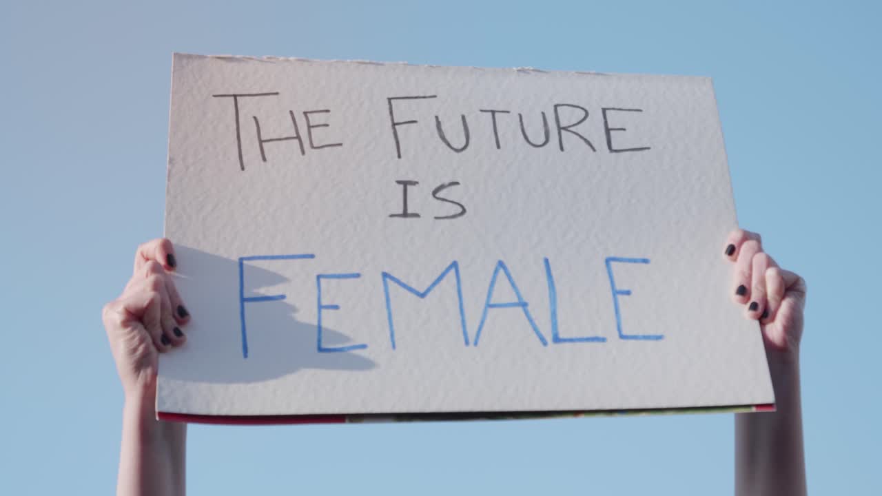 Hands Holding 'The Future Is Female' Sign Against Blue Sky