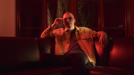 man sitting on a couch in a red lit room