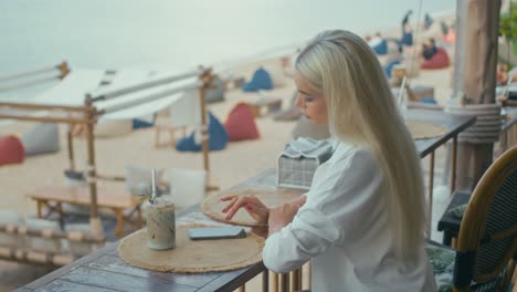 woman using phone at beach cafe