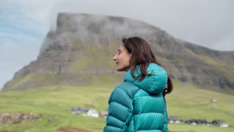 una persona disfruta de una vista serena de la montaña en un valle verde con una chaqueta azul azul al aire libre