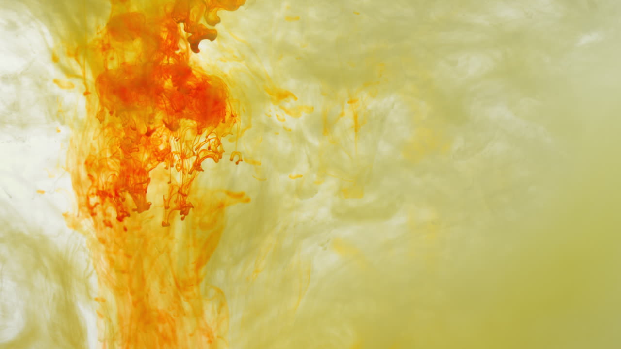желтая и оранжевая краска или краситель падают в воду на белом фоне, чтобы создать крутящийся красочный дымовый фон 2