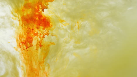 pintura o tinte amarillo y naranja caído en el agua contra un fondo blanco para crear un fondo de humo de colores giratorios 2