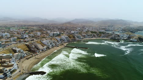 aerial circling shot of the coast of hazy san bartolo, sunny day in peru