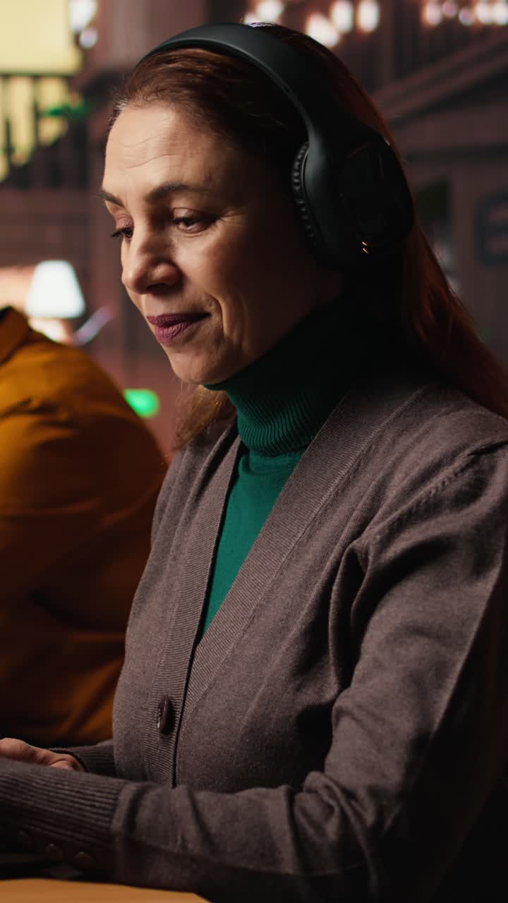 Vertical Video Mature student listening to school webinar on laptop at a library