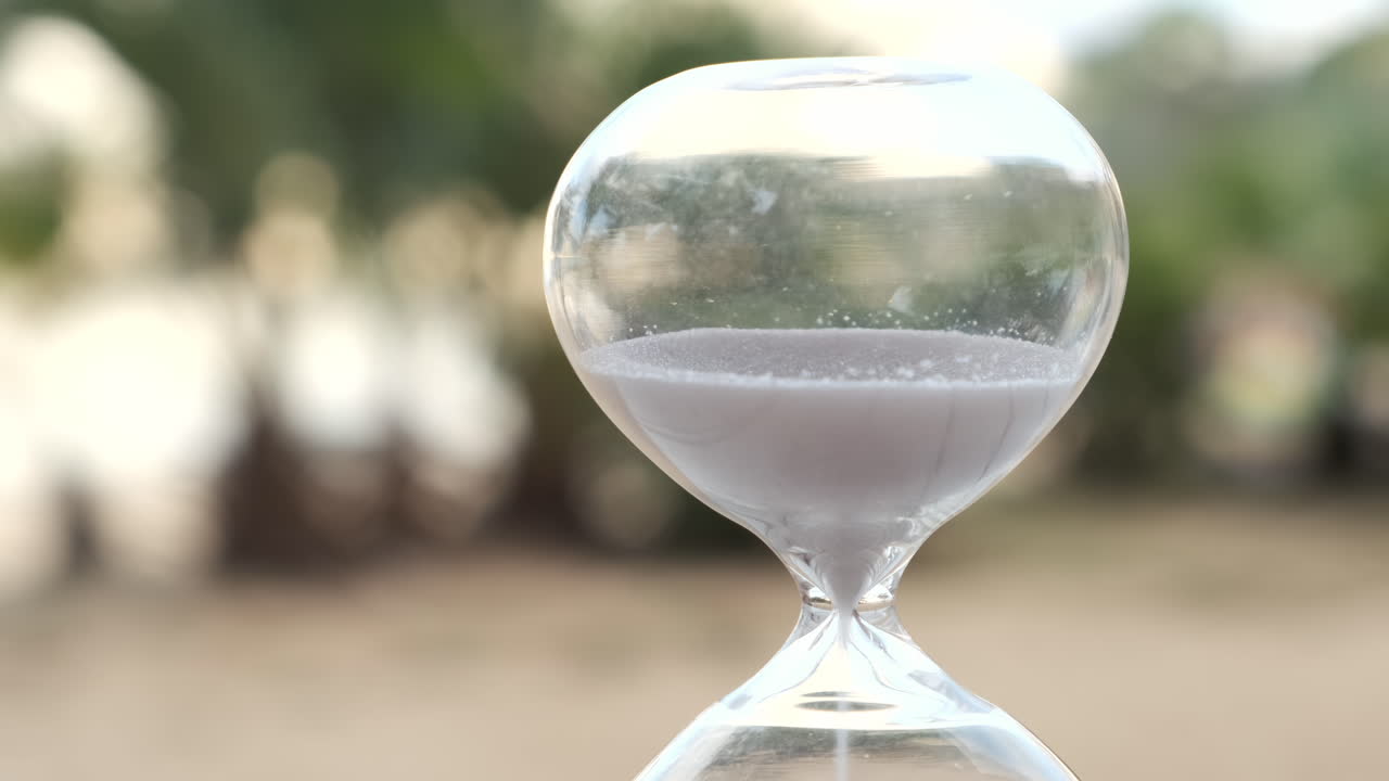 Hourglass as time passing on wooden table with bokeh background
