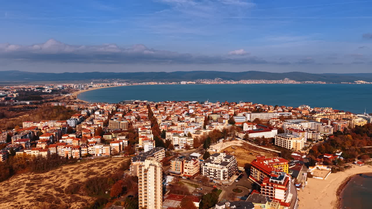 Højt luftfoto af Sunny Beach resortbugt. Oversigt over Sunny Beach by med hoteller, sandstrand og Balkanbjergene i baggrunden