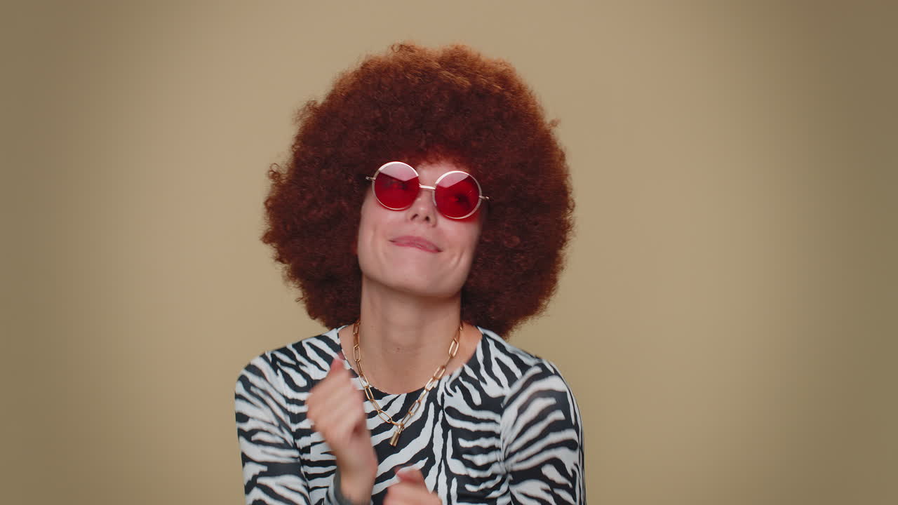 joven feliz con peluca marrón exuberante escuchando música y bailando discoteca divirtiéndose