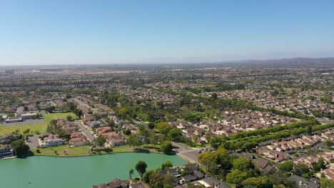 drone flying over woodbridge north lake over houses, with blue skies, green lake, and sunny 2022 summer day