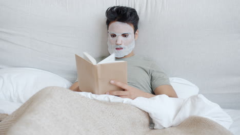 man reading in bed with face mask