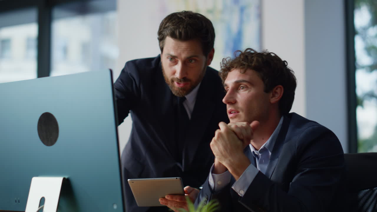 Boss showing colleague tablet ideas discussing project in modern office closeup