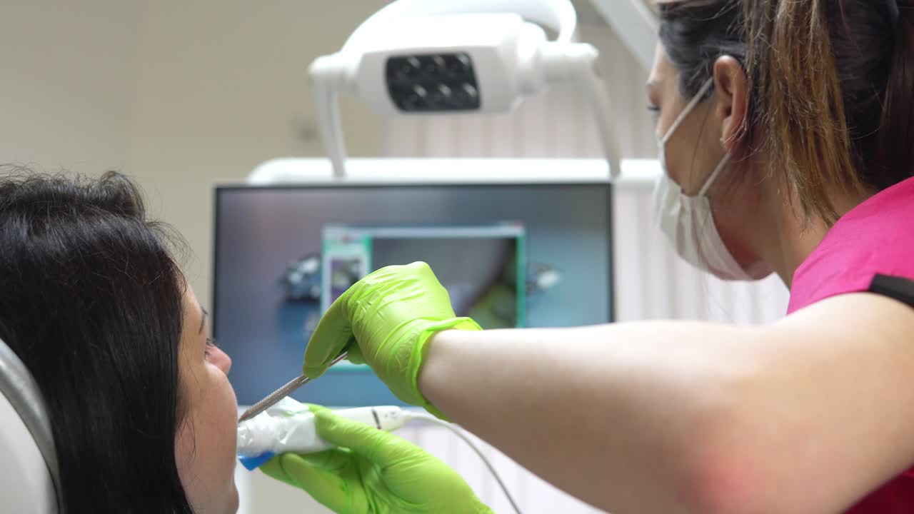 joven dentista examinando la boca de un paciente con una cámara intraoral y mostrando la imagen en la pantalla. filmado en 4k