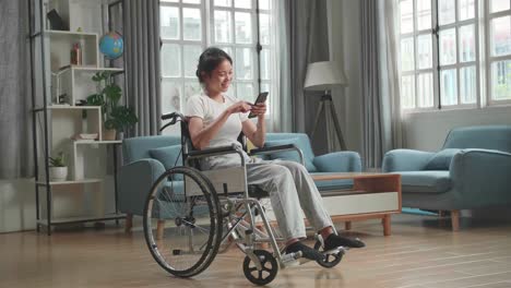 mujer usando un teléfono inteligente en una silla de ruedas en casa