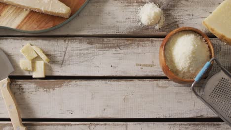 video of parmesan cheese and grated parmesan in bowl with grater on rustic table with copy space