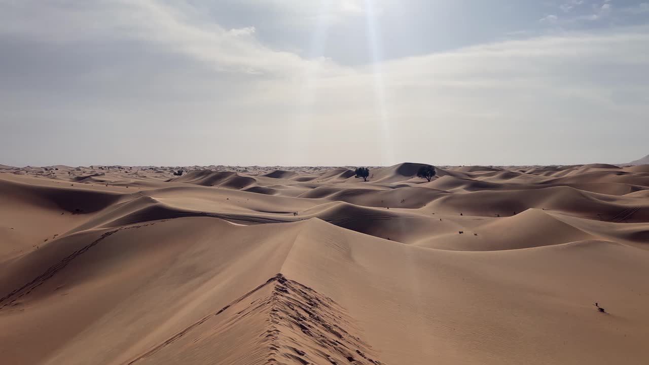 acercarse lentamente a la arena ondulada del desierto bajo un cielo azul claro, copiar el espacio