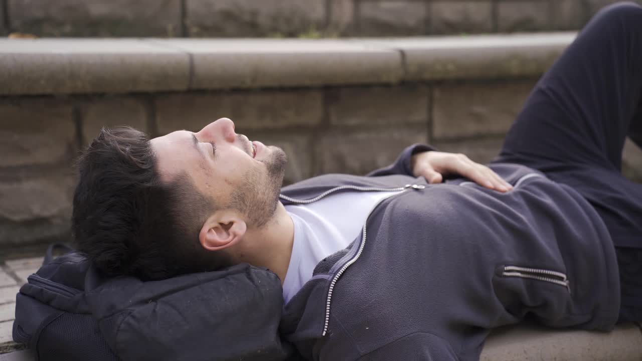 Young man lying on the ground outdoors, looking at the sky.