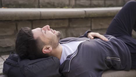 young man lying on the ground outdoors, looking at the sky.