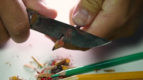 Footage-of-hands-slowly-sharpening-a-pencil-and-some-coloured-pencils-with-a-sharp-knife