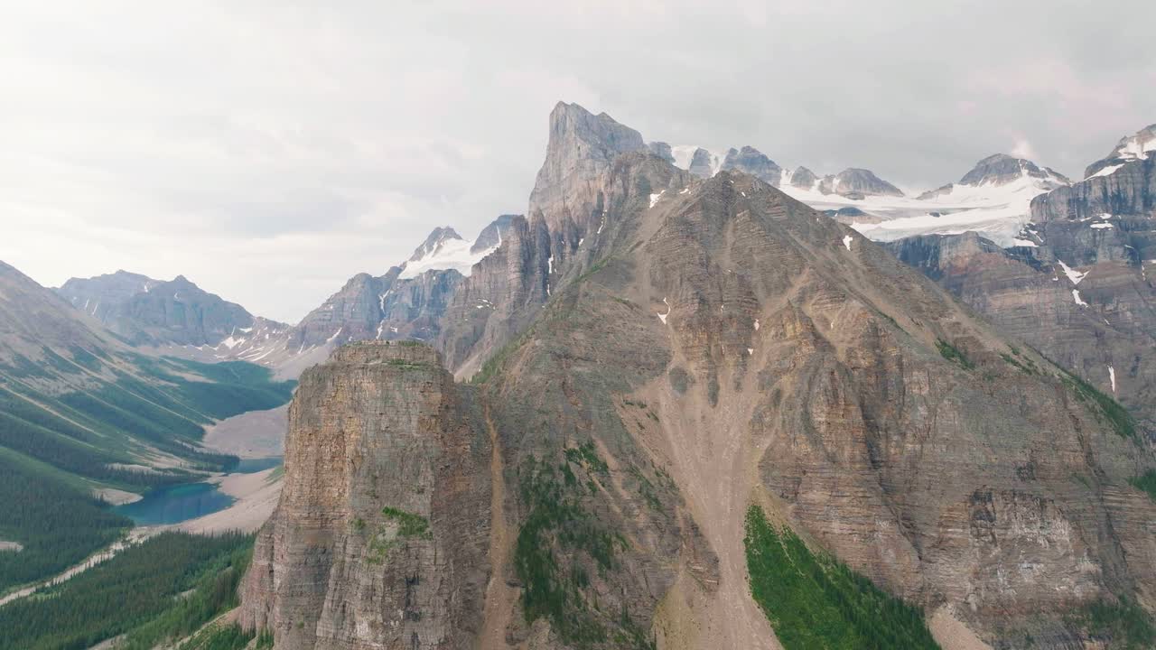 Orbita aerea delle cime innevate della catena montuosa delle Montagne Rocciose Canadesi e della foresta di pini nel Parco Nazionale di Banff, Alberta, Canada
